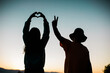 © Cavan Images - Love and Peace Sign Silhouettes with Colorful Sky - Young People