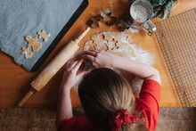 Young Girl Cutting Out Gingerbread Dough On A Wooden Table