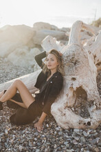 Tanned Girl Sitting On The Beach Leaning On A Log In The Sun