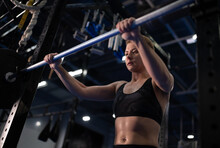 Exhausted Female Athlete Taking Barbell From Rack