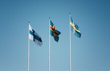 3 Skandinavian Flags Flying Together Against A Blue Sky In Finland