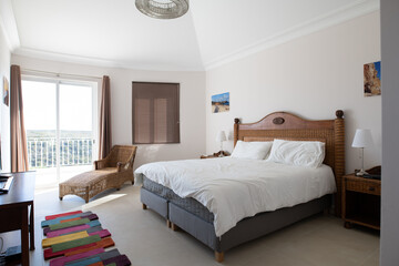 Wall Mural - Master bedroom with wooden furniture, white bedding and sliding doors to terrace in a renovated holiday villa