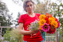A Woman Gardener Holds Out A Bright Bouquet Of Wildflowers