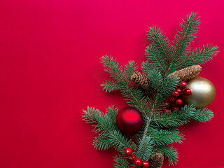 Christmas tree branches with Christmas balls and pine cones on red background. Flat lay mock up with copy space.