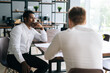 © dikushin - Pensive serious professional African American man interviewing caucasian European young candidate for job at successful company. Two business people talking strategy sitting at office desk.