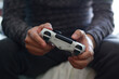 © Cavan Images - A man holding a game controller. A young man playing video games,