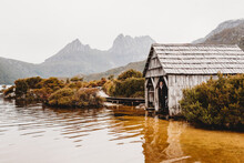 Woman Standing Inside The Old Boat Shed Next To Lake On A Wintery Day