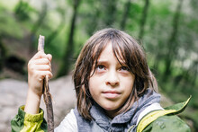 Close Up Boy Looking Up Holding Cane Stick With Wet Hair At Forest