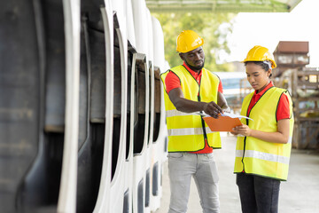 African American male and female worker in safety vest and helmet working with clipboard at automotive spare parts warehouse. people, car service, repair and maintenance concept