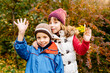 © Iryna - Funny cute little boy and girl waving hands, embracing in autumn park, happy cheerful kids brother with sister having fun together looking at camera outdoor, children siblings portrait