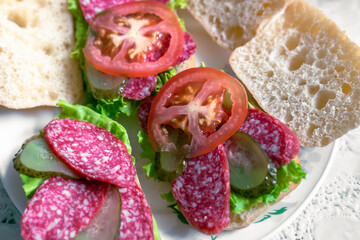 Wall Mural - Preparation of sandwiches. Preparing sandwiches with salami, tomato, pickles and lettuce