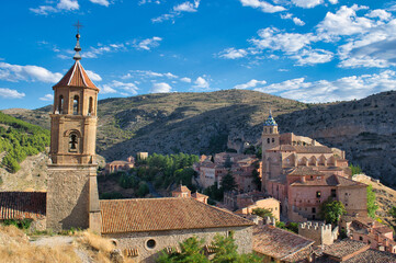 Leaning bell tower of the Santa Maria y Santiago parish in the beautiful medieval town of Albarracin, Teruel. Salvador Cathedral in the background on a hill, Spain