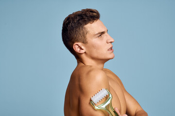 naked man with a massage instrument in his hand on a blue background emotions open mouth model