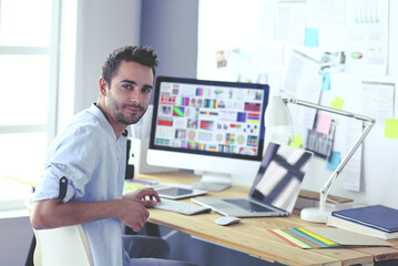 Poster - Portrait of young designer sitting at graphic studio in front of laptop and computer while working online.