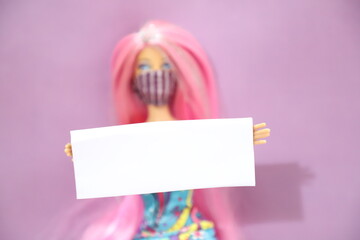 A pink haired doll wearing a mask and holding a white clean banner to add or write text