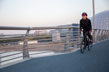 Woman training on a bicycle in the city at dawn. Yacht bridge St. Petersburg