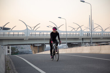 The girl rides a bicycle over the bridge. Morning workout in the city on a bike. Krestovsky Island St. Petersburg.