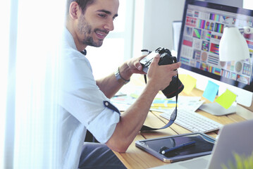 Poster - Portrait of young designer sitting at graphic studio in front of laptop and computer while working online.