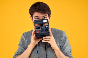 Poster - Male photographer with professional photo camera. Professional Creative approach studio yellow background