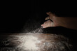 closeup of hand sprinkling flour on table with black background córdoba argentina