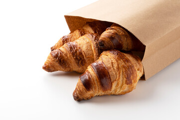 Wall Mural - A croissant in a paper bag on a white background