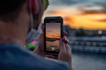 Wall Mural - closeup of a person recording the sunset on their phone