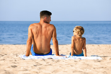 Sticker - Father and son on sandy beach near sea. Summer holidays with family