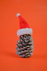 Sticker - Christmas and New Years festive time. Big spruce cone in a red santa claus hat on a bright red background.Winter holidays 