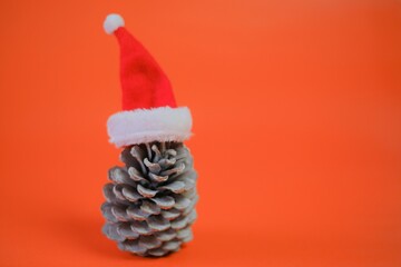 Sticker - Christmas and New Years festive time. Big spruce cone in a red santa claus hat on a bright red background.Winter holidays time.