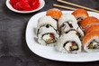 sushi rolls on a white plate on a black background with pickled ginger