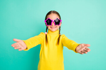 Portrait of happy smile brown haired little girl wear star glasses yellow turtleneck hug welcome you isolated on shine teal color background