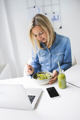 Wall Mural - Woman eating healthy salad in office in front of the laptop