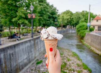 Sticker - Closeup shot of a female hand holding white ice cream on a waffle cone