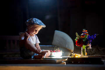 Poster - Cute beautiful child, blond kid, reading book and playing with construction blocks in a cozy attic room