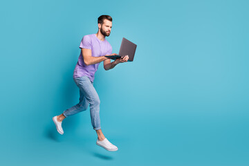 Poster - Full length body size photo of focused jumping man typing working on laptop isolated on bright blue color background