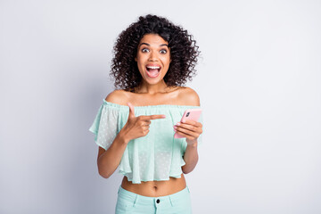 Poster - Photo portrait of screaming girl pointing finger holding phone in one hand isolated on white colored background