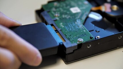 Poster - Close up of green electronic circuit board connected by the male hand to an external adapter. Media. Concept of modern technologies and engineering.