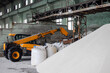 © kyrychukvitaliy - Loader loading jumbo-bags with white urea fertilizer in the warehouse. Selective focus.