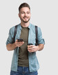 © kite_rin - Young handsome man with backpack holding smart phone and coffee. Smiling student going on a travel. Isolated on white background