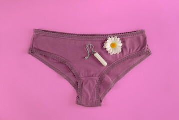 Medical female tampon and a flower on the purple panties