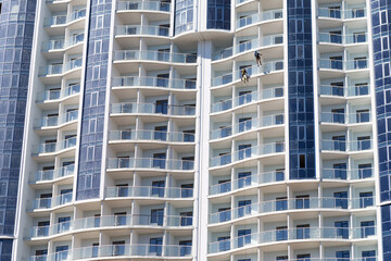 Industrial climbers working on constructing skyscraper over blue sky.