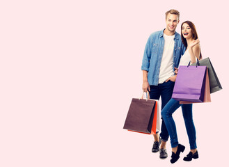 Wall Mural - Happy couple with shopping bags, standing close to each other, with copyspace for slogan or text message, isolated over pink background. Love, holiday sales, shop, retail, consumer studio concept.