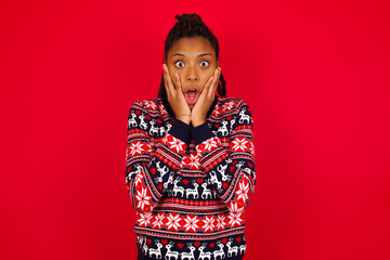 Wall Mural - Scared terrified Young beautiful African American woman standing against red background shocked with prices at shop, People and human emotions concept