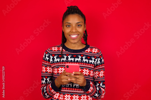 Cuadros en Lienzo Young beautiful African American woman standing against red background enjoys di