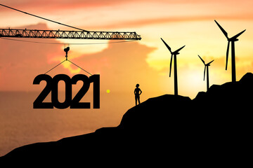 Concept Happy new year Silhouette of engineer and construction to create lifting crane 2021 on mountain slope, sunrise background.