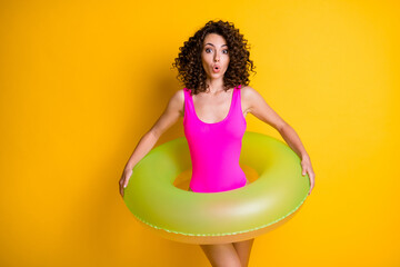 Wall Mural - Photo of attractive funny terrified lady relax rest resort prepare swim big round circle afraid step into water frightened face wear pink swimsuit isolated vivid yellow color background