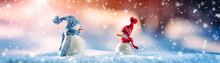 Little Knitted Snowmen On Soft Snow On Blue Background