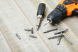 © Natasha - electric screwdriver, self-tapping screws, screwdriver bits, tool box on a wooden background