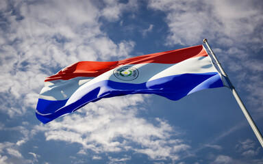 National state flag of Paraguay fluttering at sky background.