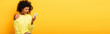 © LIGHTFIELD STUDIOS - upset african american woman looking at smartphone on yellow, banner